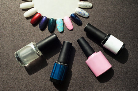 Tools for UV light manicure / pedicure. Set of gel nail polish on black background. Base coat, top...