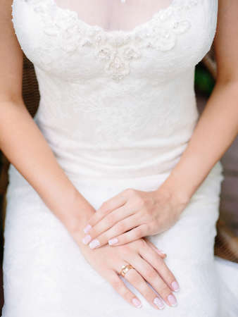 Young bride waiting for groom before wedding ceremony. Engagement ring closeup. White wedding dress with elegant lace and shining crystals.の写真素材