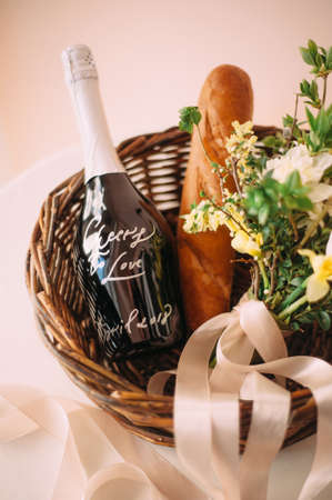 Engagement idea. Romantic picnic for two lovers. Wicker basket with two glasses of champagne with flowers, fresh baguette and a bottle of champagne. Valentines dayの写真素材