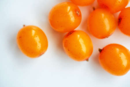 Sea buckthorn, macro view. Isolated layout on white background, top view. Raw orange berries in bright sunlight. Natural valuable food supplement.の写真素材