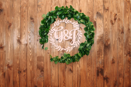 Beautiful green leaves decoration on wooden background, letters G and J, monogram emblem close up. Rustic wedding styleの写真素材