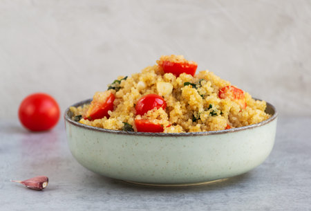 Quinoa dish on a gray background. Healthy vegetarian recipe with cereal and vegetables: tomatoes,...