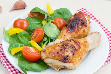 Two grilled chicken legs with vegetable saladの写真素材