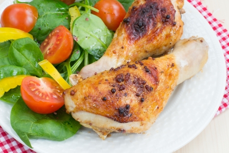 Two roasted chicken legs and salad from fresh vegetables の写真素材