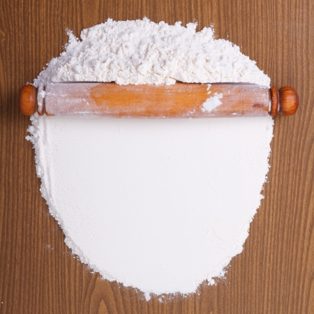 Wooden rolling pin with white wheat flour on the table  top viewの写真素材