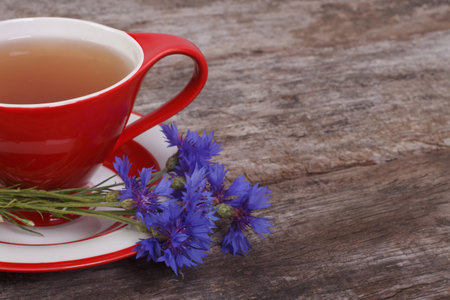 Herbal tea and a bouquet of cornflowers on the old boardの写真素材