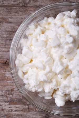 cottage cheese in a glass bowl on old wooden table closeup. macro. view from above. vertical
の写真素材
