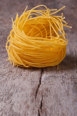 dry yellow pasta nest close up on an old wooden table. macro. upright
の写真素材