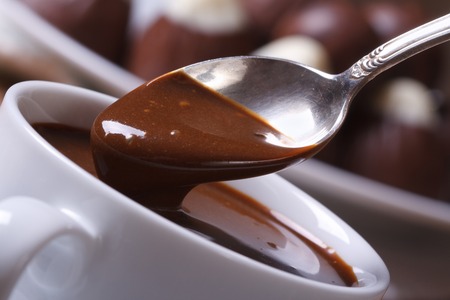 Spoon with liquid chocolate and cup closeup horizontal. macro 
の写真素材