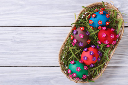 Easter eggs decorated with flowers in a basket on a wooden table top view