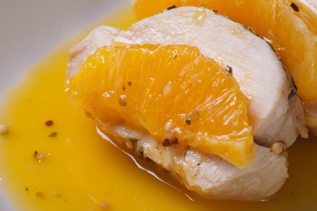 Piece of meat with sauce and a slice of orange on a white plate macro. horizontal
の写真素材