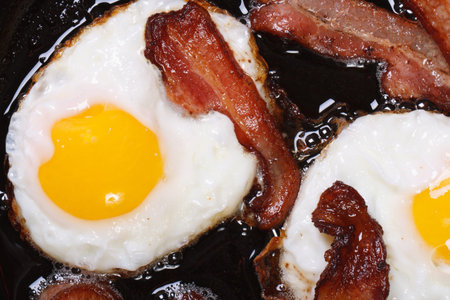fried eggs with bacon in a pan close-up. top viewの写真素材