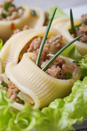 Italian pasta lumakoni stuffed meat and onion closeup with lettuce leaves. vertical macro 
の写真素材