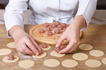 Cook hands closeup lay out minced meat on dumplings
の写真素材