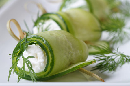 Cucumber rolls with cheese and dill closeup on a white plate. horizontal 