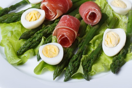 Boiled quail eggs with ham and asparagus on a plate close-up view from aboveの写真素材