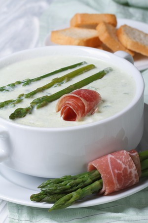 Asparagus cream soup with ham closeup in white bowl and croutons. vertical 
の写真素材