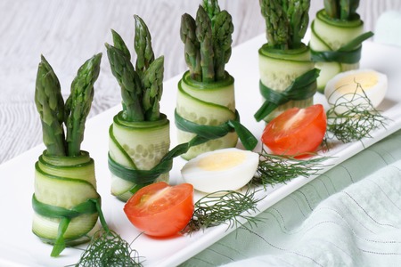 Rolls of fresh cucumber with green asparagus on a plate with quail eggs and tomatoes. horizontal
の写真素材