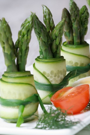 Snack: cucumber rolls with asparagus and green onions on a plate macro vertical.
の写真素材