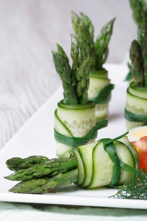Appetizer buffet: beautiful cucumber rolls with asparagus and green onions on a plate closeup vertical
の写真素材