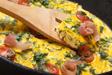 Omelette with tomatoes, ham and herbs closeup on wooden spatula. horizontal 
の写真素材