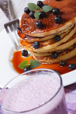 Blueberry cocktail and pancakes with berries and maple syrup on the table closeup. vertical 
の写真素材