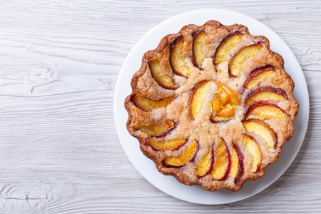 round peach pie on a wooden background horizontal view from aboveの写真素材