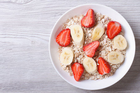 muesli with fresh strawberries and banana closeup on wooden background. horizontal top view 