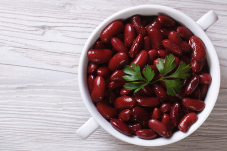 boiled red kidney beans in a white bowl closeup on wooden background horizontal view from above