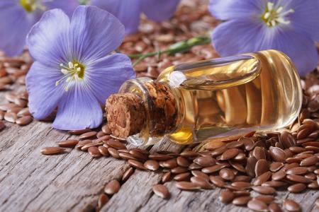 flax seeds, blue flowers and oil in a bottle on the table 
の写真素材