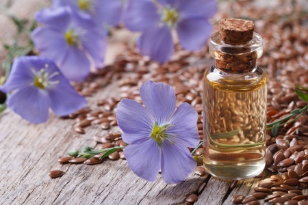 flax oil in a glass bottle closeup on a background of flowers and seeds の写真素材