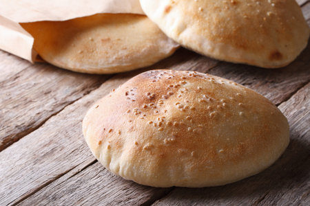Fresh tasty pita bread on the wooden table closeup horizontal