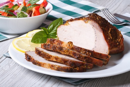 Tasty juicy roast pork tenderloin and salad on the table. Horizontal close-up
の写真素材