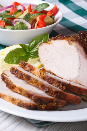 Tasty juicy baked pork fillet and salad on the table. vertical close up
の写真素材
