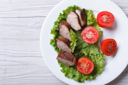 duck meat fried with tomatoes close-up on white plate from above. horizontalの写真素材