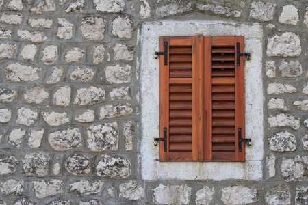 Window Closed brown shutters on a stone wall of a house close-upの写真素材