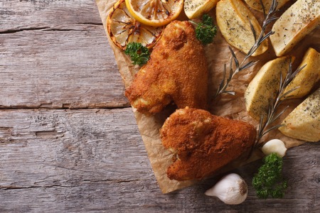 Fried chicken wings dipped in batter, with potato and lemon horizontal view from aboveの写真素材