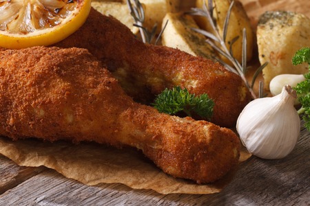 fried chicken leg dipped in batter, served with potatoes and lemon close up horizontalの写真素材