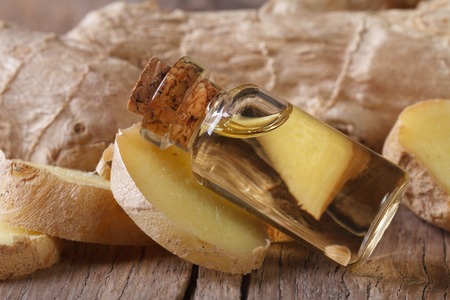 Useful ginger oil in a glass bottle with cork macro on an old table horizontalの写真素材