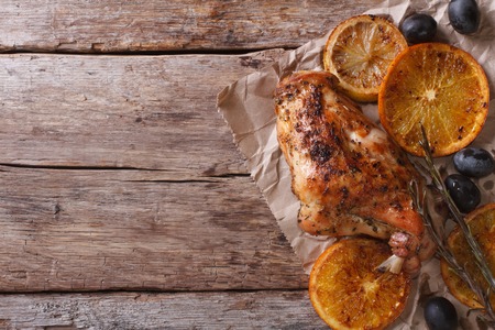 roasted rabbit leg with oranges and olives on an old table. horizontal view from aboveの写真素材