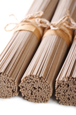 Raw buckwheat soba noodles macro in bunches isolated on white backgroundの写真素材