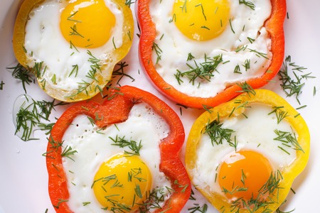 fried eggs with yellow and red peppers macro. horizontal view from aboveの写真素材