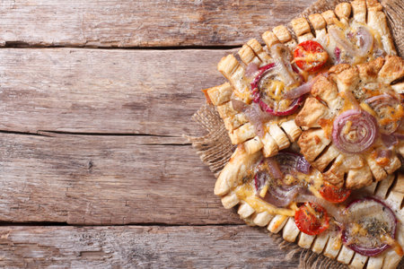 Puff pastry pies with red onions and tomatoes on the table. horizontal view from above, rustic style