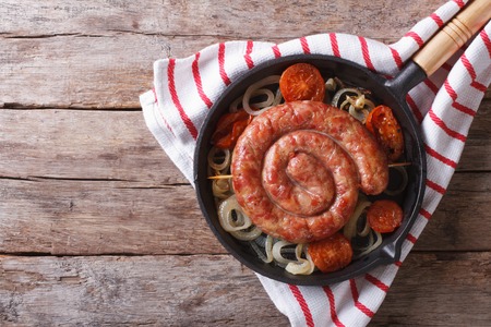 Grilled sausage with onions and tomatoes in a pan. horizontal view from aboveの写真素材
