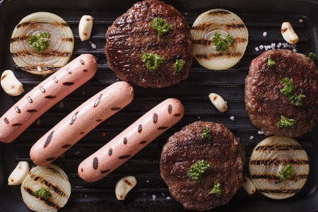 grilled burgers and sausages on the grill close up. horizontal view from aboveの写真素材