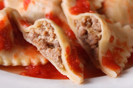 Ravioli stuffed with meat in tomato sauce on a plate macro. Horizontalの写真素材