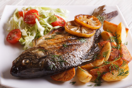 fried fish carp with potato and salad on a plate close-up. horizontal