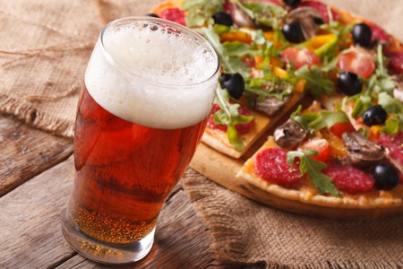 Cold beer and hot pizza with arugula on the table close-up horizontal. rustic styleの写真素材