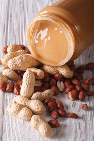fresh peanut butter in a glass jar and nuts close-up on the table. verticalの写真素材