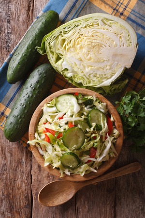 Coleslaw in a wooden bowl and ingredients on the table, the vertical view from aboveの写真素材